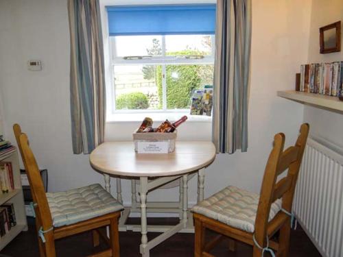 バーナード・キャッスルにあるCurlew Cottageのテーブルと椅子2脚、窓が備わる客室です。
