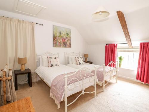 a white bedroom with two beds and a window at Manor Farm Cottage in Swaffham