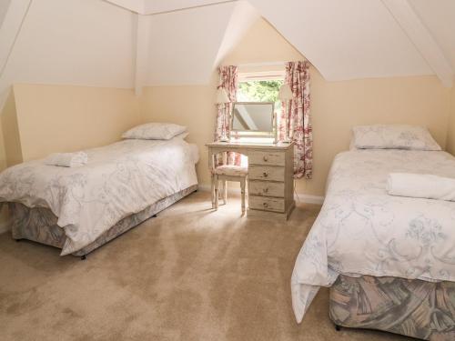 a bedroom with two beds and a dresser and a mirror at Riverside Cottage in Llandrindod Wells