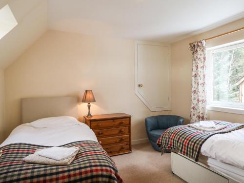 a bedroom with two beds and a blue chair at Newlands in Archiestown