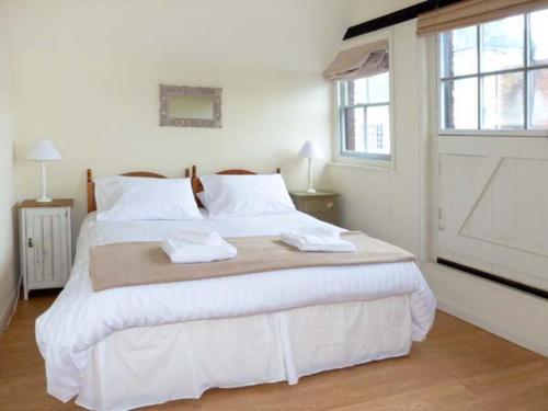 a white bedroom with a large bed with two towels on it at The Old Forge in Rye