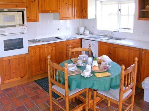 een keuken met een tafel en stoelen en een keuken met bij The Bothy in Lymington