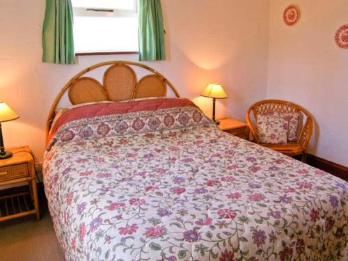 ein Schlafzimmer mit einem großen Bett mit einer Blumenbettdecke in der Unterkunft The Bothy in Lymington