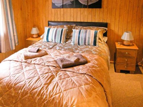 a bedroom with a bed with pillows and two lamps at Lake View Lodge in Shepton Mallet