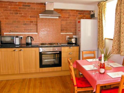 a kitchen with a table and a kitchen with a stove at Pear Tree Cottage in Ellesmere