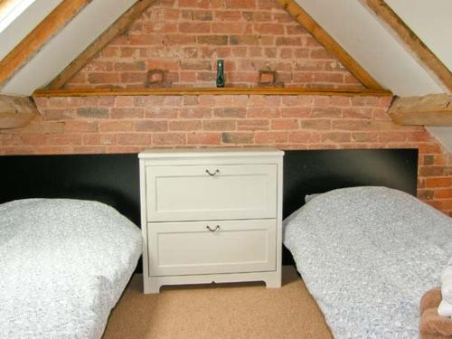 a bedroom with two beds and a brick wall at Pear Tree Cottage in Ellesmere