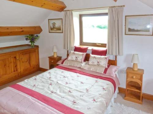 a bedroom with a large bed and a window at Mews Cottage in Penrith