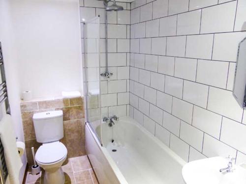 a bathroom with a toilet and a tub and a sink at The Old Stable in Weston-super-Mare