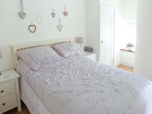 een wit bed in een witte slaapkamer met een wit bedframe bij The Gatehouse in Leyburn