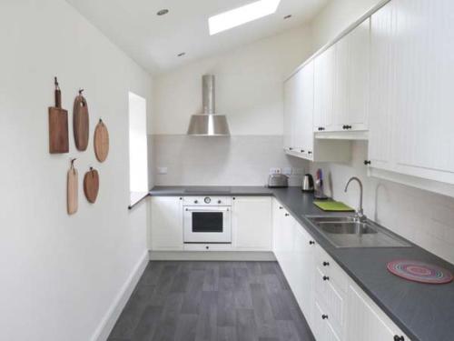 een witte keuken met een fornuis en een wastafel bij The Gatehouse in Leyburn