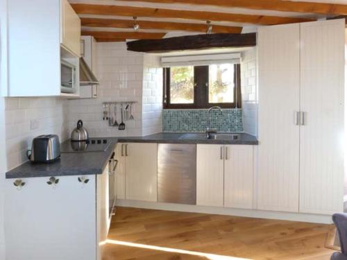 a kitchen with white cabinets and a sink and a window at The Round House in Leyburn