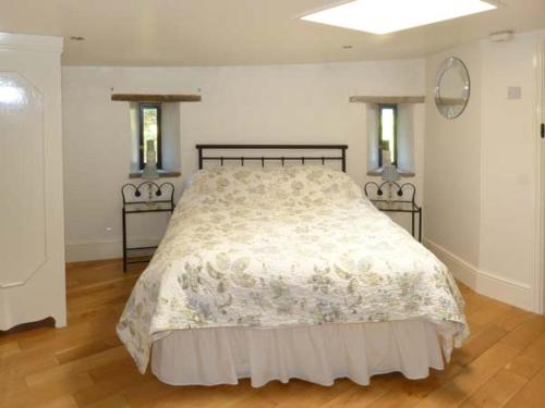 a bedroom with a bed with a white comforter and two windows at The Round House in Leyburn