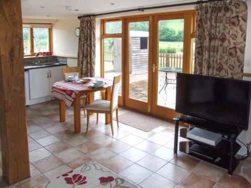 Mallard في Newnham: غرفة معيشة مع طاولة ومطبخ مع تلفزيون