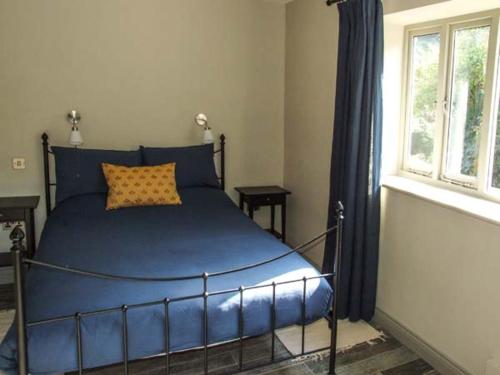 een blauw bed in een slaapkamer met een raam bij The Stable in Ross on Wye