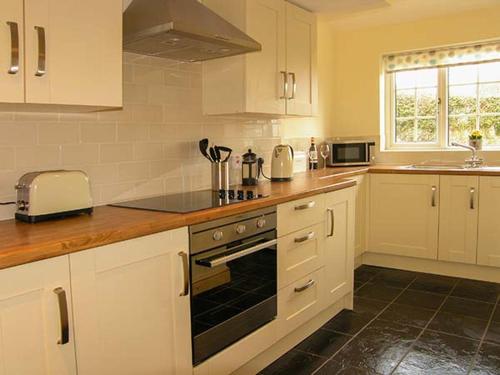 a kitchen with white cabinets and a stove top oven at Ty Cerrig in Mold