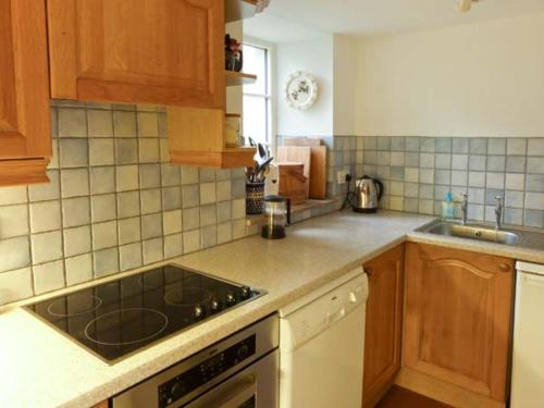 a kitchen with wooden cabinets and a stove top oven at Farrier's Cottage in Sedbergh