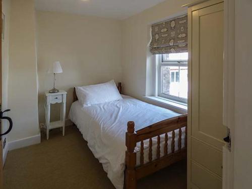 a small bedroom with a bed and a window at Bakers Cottage in Newbiggin