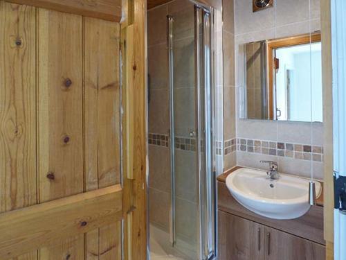 a bathroom with a sink and a shower and a mirror at Bakers Cottage in Newbiggin
