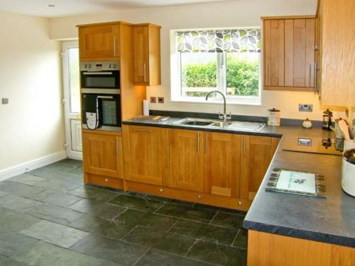 a kitchen with wooden cabinets and a sink and a window at Hendre in Denbigh
