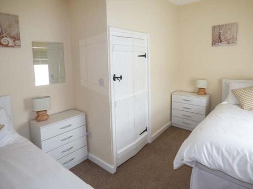 a bedroom with two beds and a mirror at Ty Twt in Burry Port