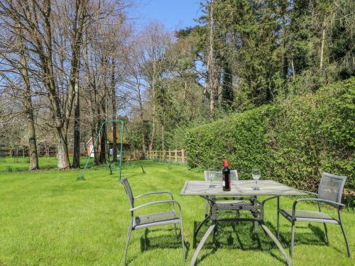 a picnic table with two chairs and a bottle of wine at The Roost in Broughton