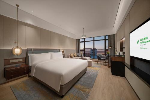 um quarto com uma grande cama branca e uma televisão de ecrã plano em Holiday Inn Changchun Jingyue, an IHG Hotel em Changchun