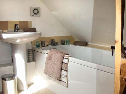 a bathroom with a sink and a bath tub with a towel at Owl Cottage in Southam