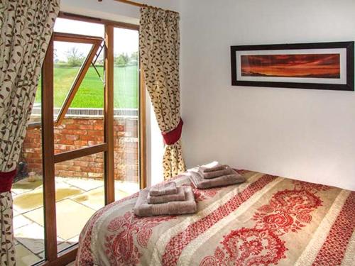 a bedroom with a bed with towels on it at Owl Cottage in Southam