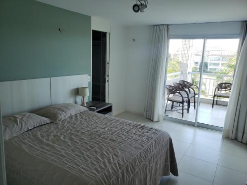 ein Schlafzimmer mit einem Bett und ein Balkon mit einem Tisch in der Unterkunft Apto Completo l Excelente Vista em Golf Ville Resort in Aquiraz