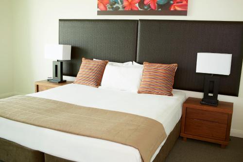 a bedroom with a large bed with two lamps on tables at Mantra Sun City in Gold Coast