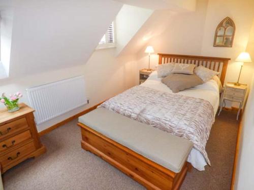 a bedroom with a bed and a dresser with two lamps at Beacon Cottage in Great Malvern