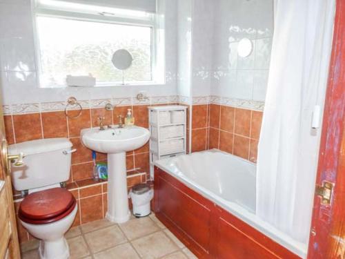 a bathroom with a toilet and a tub and a sink at Chapel Cottage in Whitby