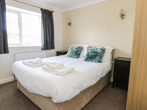a bedroom with a bed with white sheets and blue pillows at Swan Cottage in Fearby