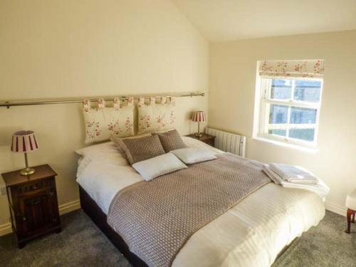 a bedroom with a large bed and a window at Old Hall Cottage in Settle
