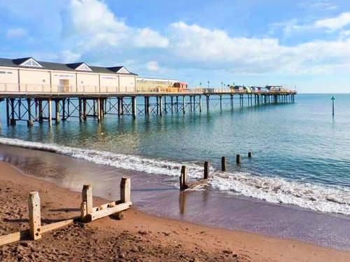 a beach with a pier in the water at Sunshine Cottage in Teignmouth