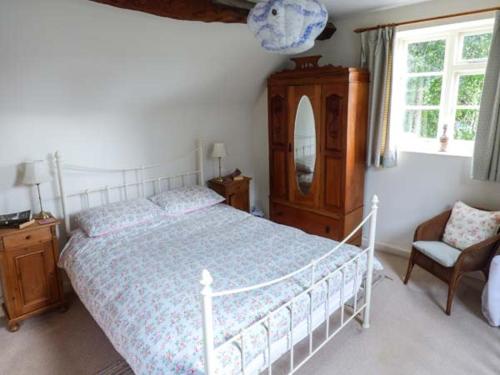 1 dormitorio con cama, silla y espejo en The Smithy, en Leominster