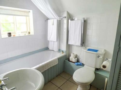 a bathroom with a toilet and a tub and a sink at The Smithy in Leominster