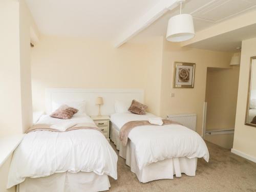 two beds in a room with white walls at Wesley Cottage in Keighley