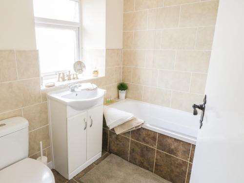 a bathroom with a tub and a sink and a toilet at Wesley Cottage in Keighley
