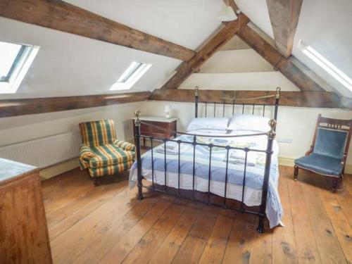 a bedroom with a bed and a chair in a attic at Tyn Llwyn in Dolgellau