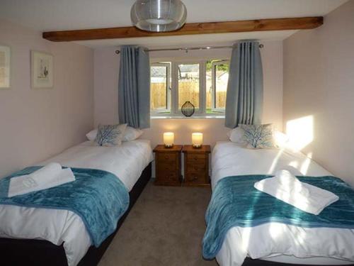 zwei Betten in einem Zimmer mit zwei Fenstern in der Unterkunft Rose Cottage in Winforton
