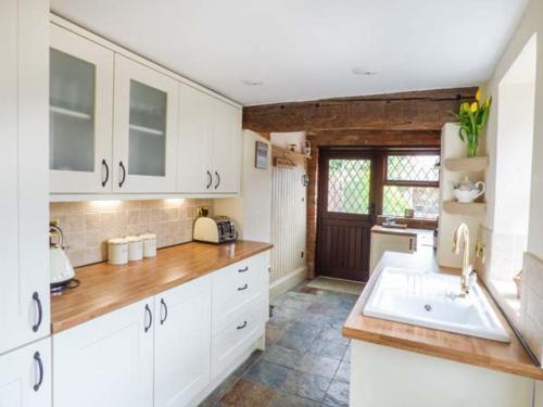 a kitchen with white cabinets and a sink at Fern Cottage in Heacham