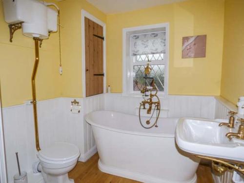 a bathroom with a tub and a toilet and a sink at Fern Cottage in Heacham