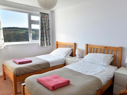 two beds in a room with a window at Treverrion in Gorran Haven