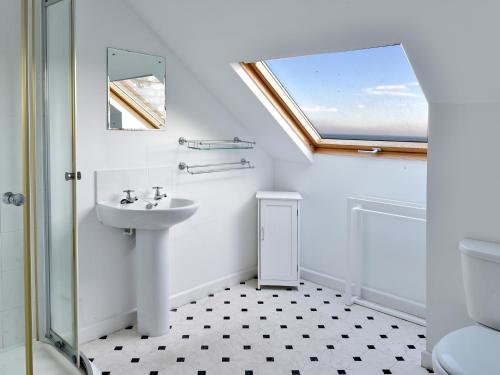 La salle de bains est pourvue d'un lavabo, de toilettes et d'une fenêtre. dans l'établissement Treverrion, à Gorran Haven