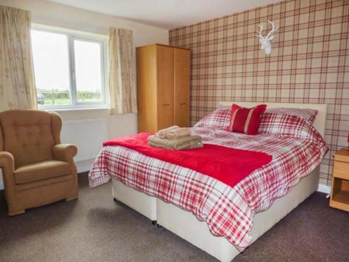 Un dormitorio con una cama con almohadas rojas y una silla en The Willows, en Ellesmere