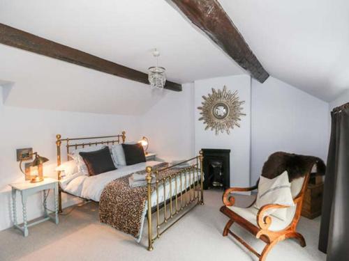 a bedroom with a bed and a chair at Rose Cottage in Bakewell