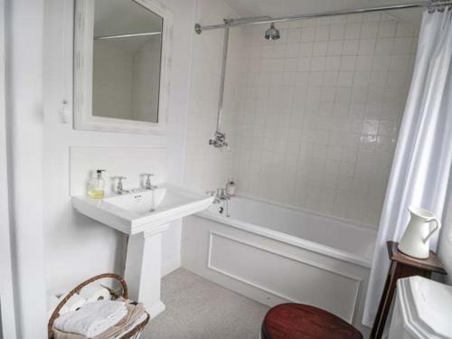 a white bathroom with a sink and a bath tub at Rose Cottage in Bakewell