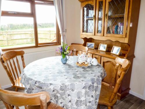 comedor con mesa, sillas y ventana en The Dovecote, en Hartland
