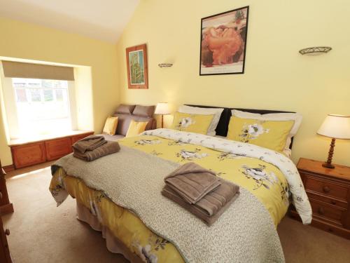 キャッスルトンにあるButtercup Cottageのベッドルーム1室(大型ベッド1台、黄色い掛け布団付)